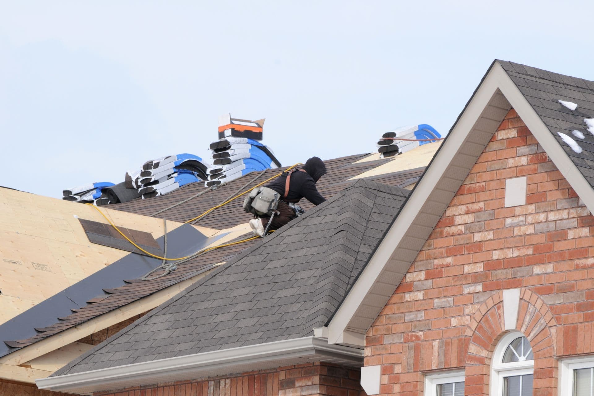 Roofing crew replacing shingles on a brick home
